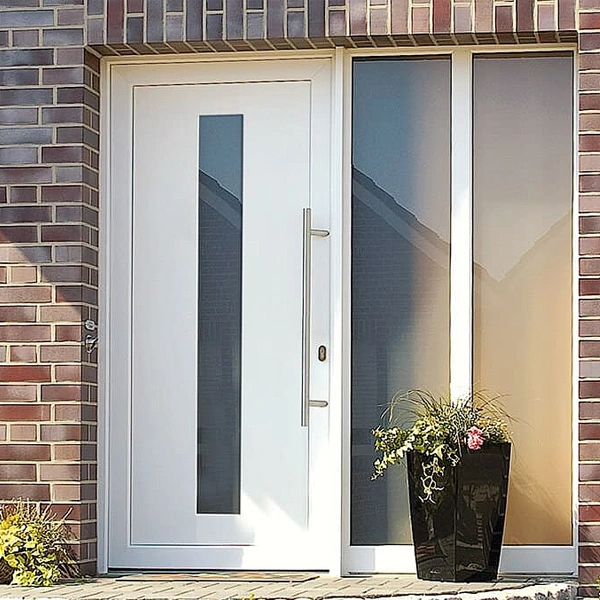 White front door with a tall vertical glass panel, flanked by sidelights, set in a brick exterior with a black planter of flowers nearby.